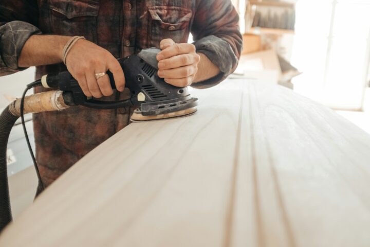 man using sander on beige wooden surface